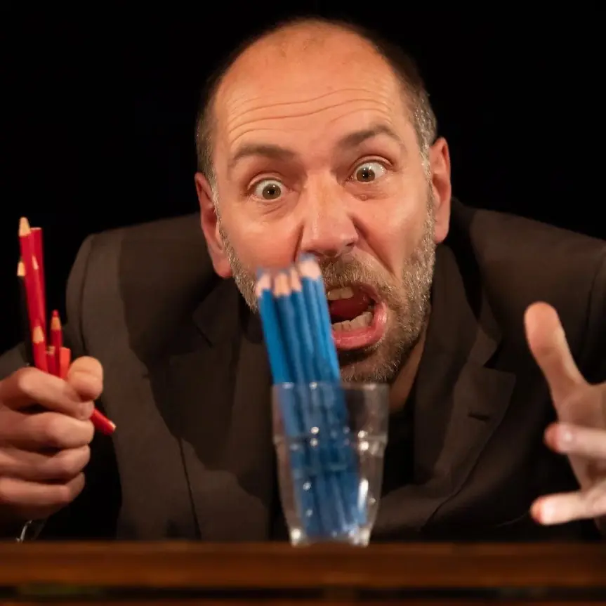 Un homme crie face à un pot de crayon bleu en tenant des crayons rouges dans sa main