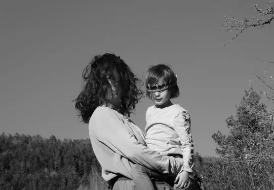 Une mère les cheveux ébourrifés porte un enfant dans ses bras